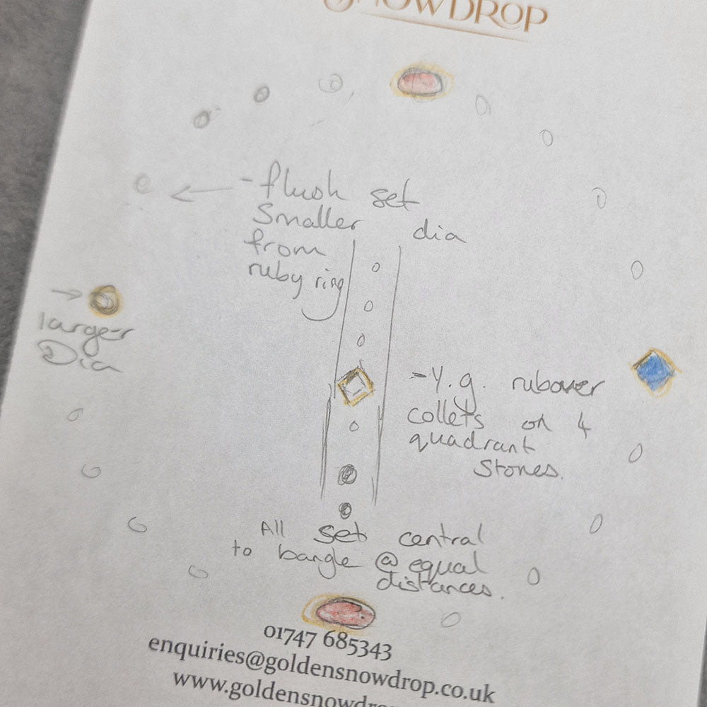 Hand drawn design sketch by our jeweller, designer and gemmologist for the Ruby, Sapphire and Diamond Hammered Bangle in Sterling Silver      with 9ct Yellow Gold Settings. 
Remodelled using our customers original gold and stones, at Golden Snowdrop the jewellers in Shaftesbury, near Blandford. 
